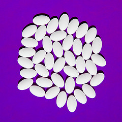 Image showing White pills group on purple background.