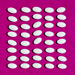 Image showing White pills on pink background.