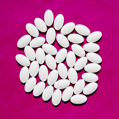 Image showing White pills group on magenta background. 