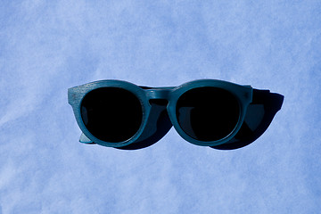 Image showing Stylish sunglasses with shadow on blue background. 