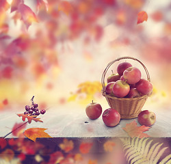 Image showing red apples in a basket and autumn leaves