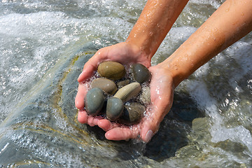 Image showing Wave covered palms with large sea pebbles