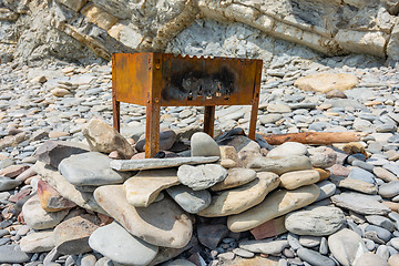 Image showing On a rocky shore is a small abandoned barbecue