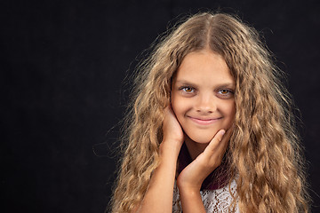 Image showing Closeup portrait of a cheerful ten year old girl on black background