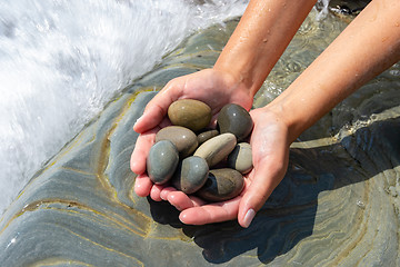 Image showing Palms hold a pile of stones on the seashore