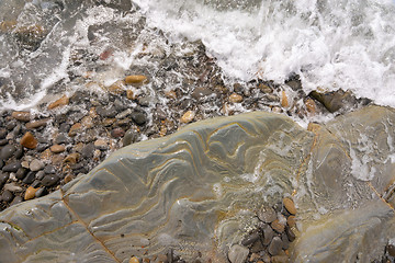 Image showing A wave rolls onto a rocky sea beach