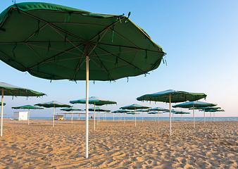 Image showing Opened sunshades of a deserted sandy beach at sunset