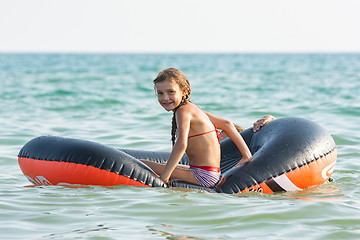 Image showing Cheerful girl rides on an inflatable boat at sea