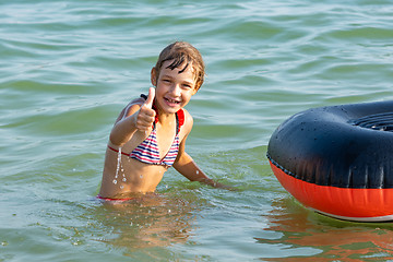Image showing Cheerful girl shows thumb up by jumping from a boat