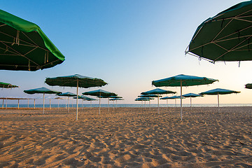 Image showing Opened umbrellas on a deserted evening sandy beach