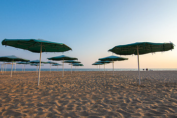 Image showing Opened sandy beach umbrellas at sunset