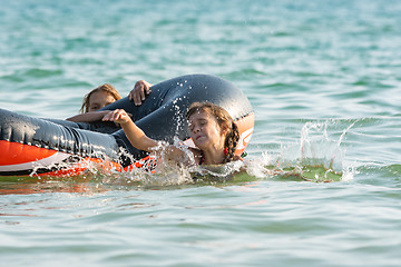 Image showing Two girls dive from an inflatable boat into the sea