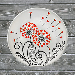 Image showing Decorative ceramic plate, hand painted with acrylic paints on a wooden background. A square photo closeup.