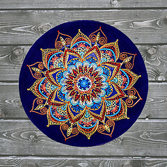 Image showing Decorative ceramic plate, hand painted with acrylic paints on a wooden background. A square photo closeup.