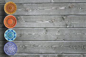 Image showing Set of decorative ceramic plates hand-painted with acrylic paints on a wooden background with place for text.