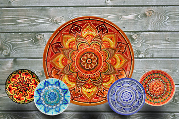 Image showing Set of decorative ceramic plates hand-painted with acrylic paints on a wooden background with place for text.