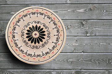 Image showing Decorative ceramic plate, hand painted with acrylic paints on a wooden background. Closeup with place for text.