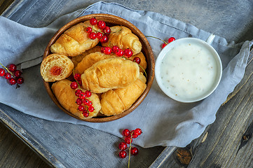 Image showing Croissants with currant berries on a wooden tray. The concept of a wholesome breakfast.