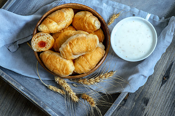 Image showing Croissants, a cup with kefir and ears of grain on a wooden tray. The concept of a wholesome breakfast.