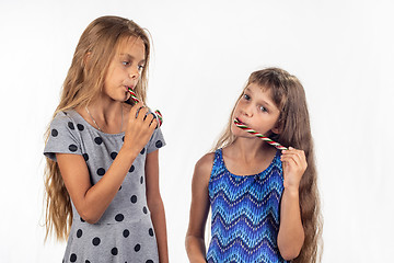 Image showing Two girls suck caramel candies