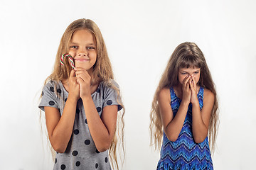 Image showing One girl was given a lollipop, the other one wasn\'t