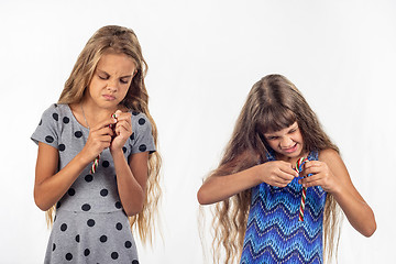 Image showing Two girls try to open a plastic bag of caramel candies