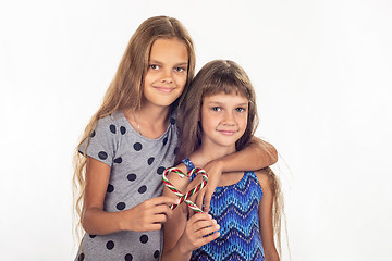 Image showing Two girls hugging made a heart out of two lollipops