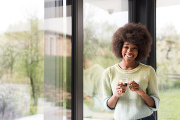 Image showing African American woman drinking coffee looking out the window
