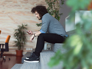 Image showing Young casual businessman holding smartphone