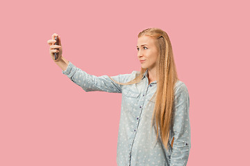 Image showing Portrait of a happy smiling casual girl showing blank screen mobile phone isolated over pink background