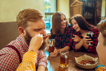 Image showing people, leisure, friendship and communication concept - happy friends drinking beer, talking and clinking glasses at bar or pub