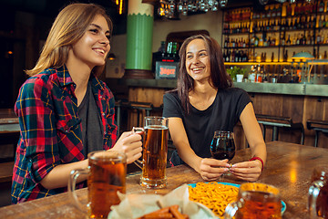 Image showing people, leisure, friendship and communication concept - happy friends drinking beer, talking and clinking glasses at bar or pub