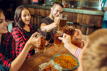 Image showing people, leisure, friendship and communication concept - happy friends drinking beer, talking and clinking glasses at bar or pub