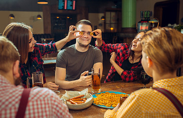 Image showing people, leisure, friendship and communication concept - happy friends drinking beer, talking and clinking glasses at bar or pub