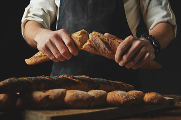 Image showing Male hands break the baguette