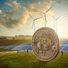 Image showing Gold coin bitcoin on a green field against the sky and solar panels. Eco mining concept