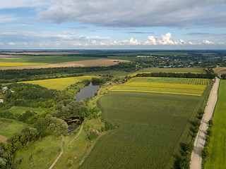 Image showing Panoramic view from drone to the countryside with a river, dirt road and agricultural fields against cloudy sky