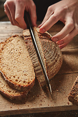 Image showing Male hands slicing homemade bread