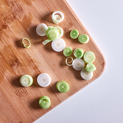 Image showing Sliced leek onions on a wooden board on a gray background with copy space. Flat lay