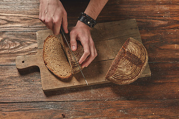 Image showing Man slicing tasty fresh bread.