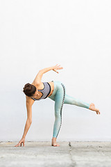 Image showing Fit sporty active girl in fashion sportswear doing yoga fitness exercise in front of gray wall, outdoor sports, urban style