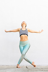 Image showing Fit sporty active girl in fashion sportswear doing yoga fitness exercise in front of gray wall, outdoor sports, urban style