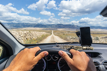 Image showing Detail of male driver hands on steering wheel. Driving a car on country road. View from the cabin trough the windshield.