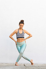 Image showing Fit sporty active girl in fashion sportswear doing yoga fitness exercise in front of gray wall, outdoor sports, urban style