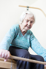 Image showing Elderly 96 years old woman exercising with a stick sitting on her bad.
