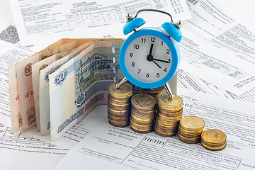 Image showing Hours, paper rubles, stacks of coins, receipt with accrued interest on electricity