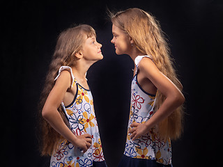 Image showing Two girls are standing opposite each other and putting their hands on their sides are looking at each other.