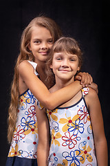 Image showing Portrait of two friendly sisters on a black background