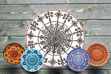 Image showing Set of decorative ceramic plates hand painted dot pattern with acrylic paints on a gray wooden background. Copy space.