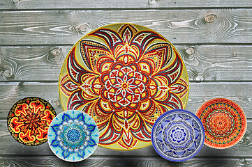 Image showing Set of decorative ceramic plates hand painted dot pattern with acrylic paints on a gray wooden background. Copy space.